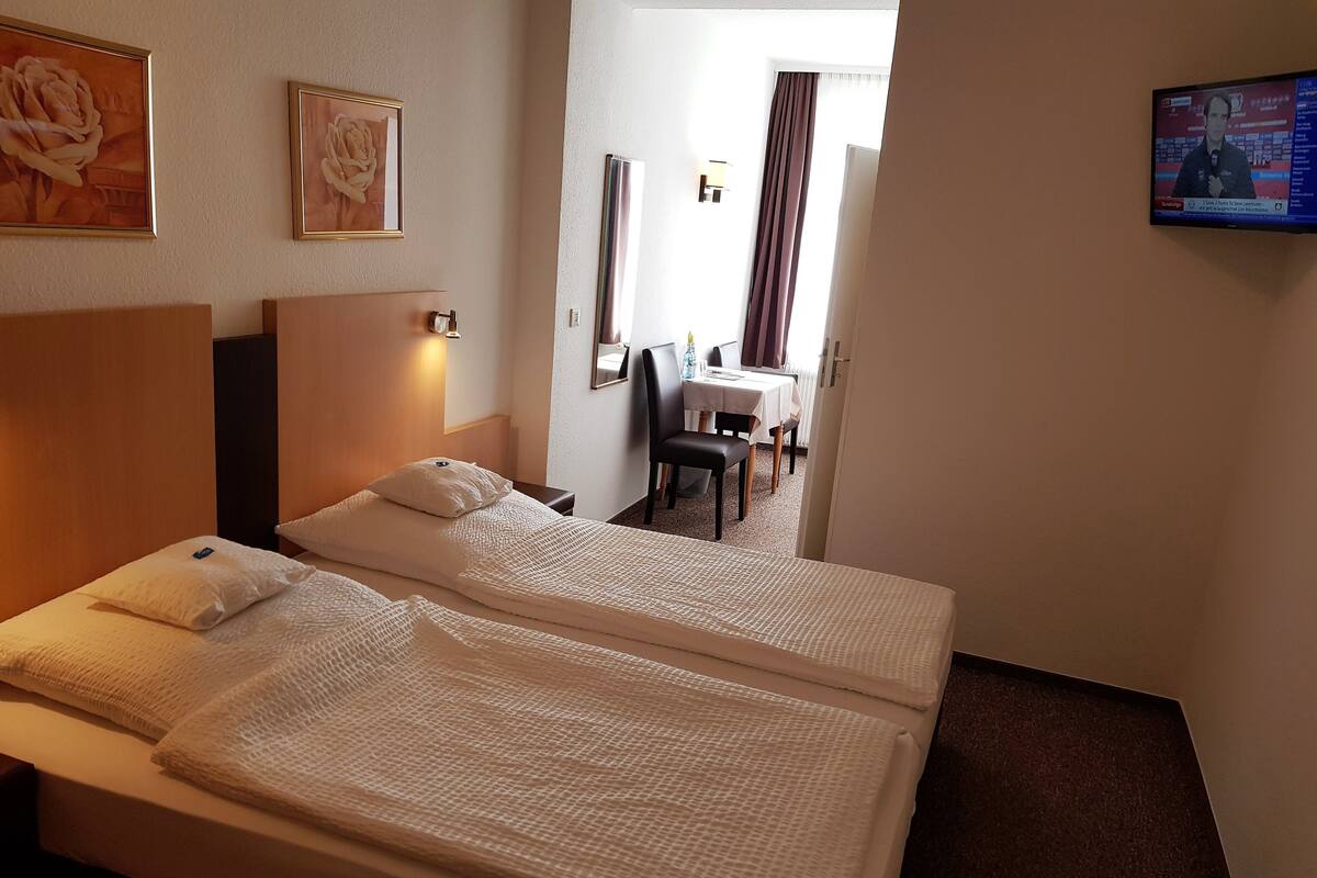 A hotel room with a large bed, a desk, and a television.