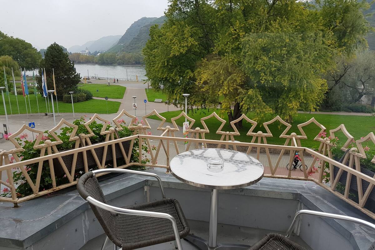An outdoor seating area with a table and chairs, overlooking a lake and greenery.