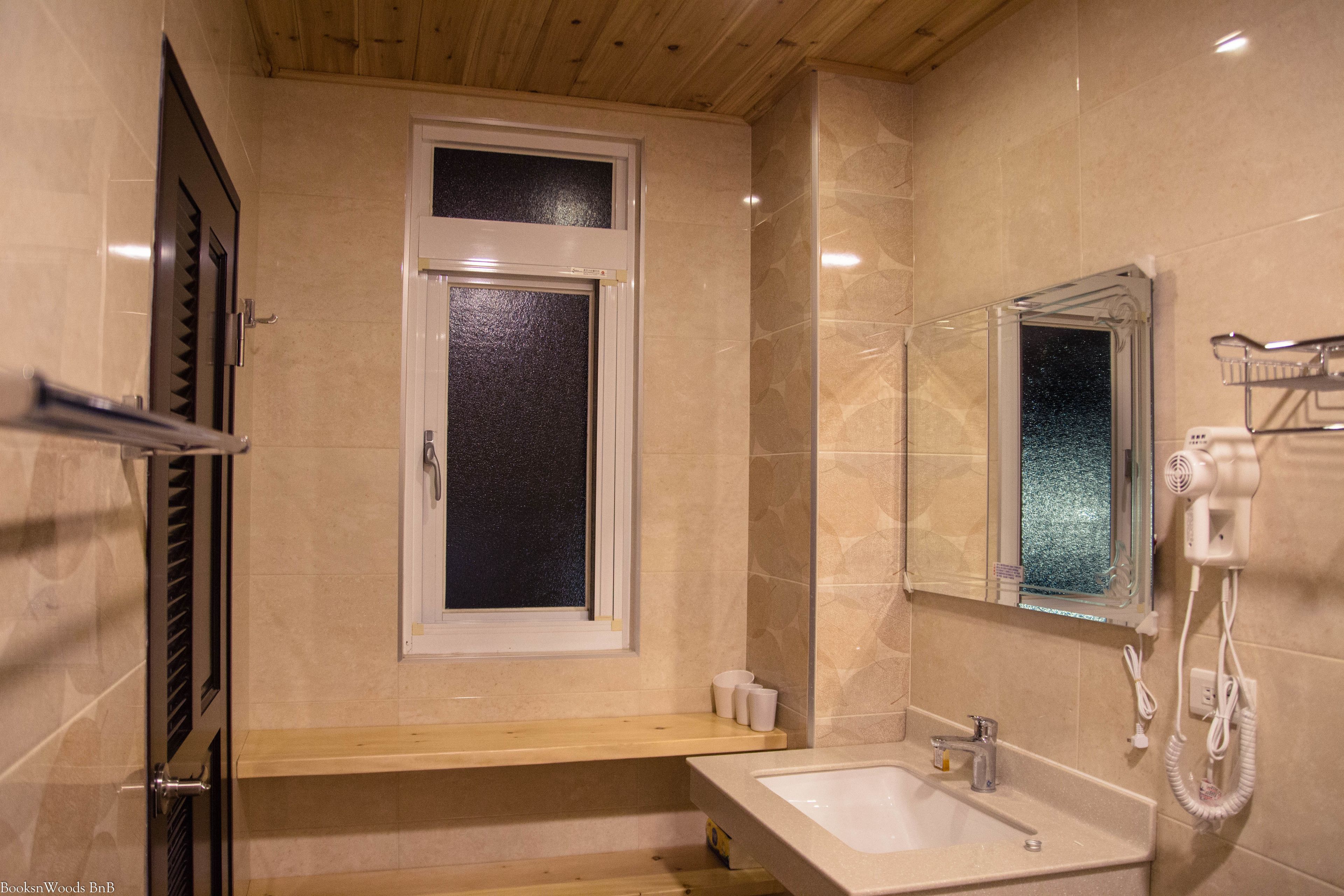A bathroom with a sink, mirror, and window.