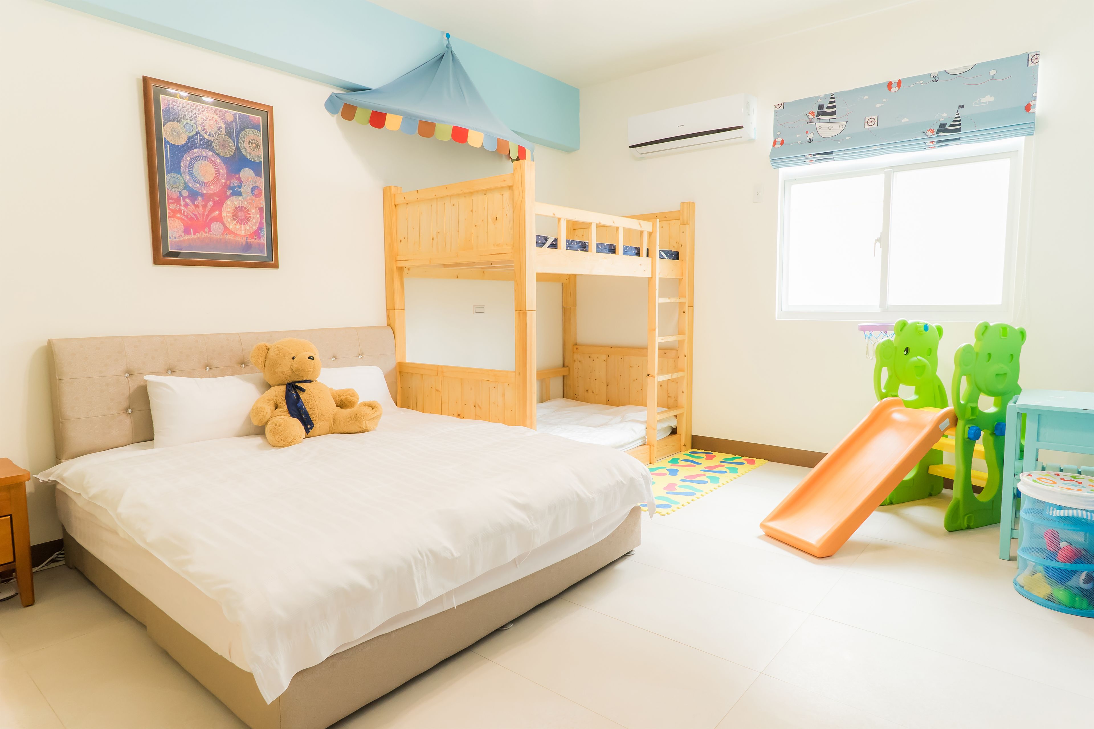A child's bedroom with bunk beds, a teddy bear, a slide, and a green toy structure.