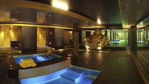 Een moderne spa met een ruime jacuzzi, een beeld en een glazen zwembad.