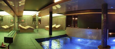 A spa area with a hot tub, seating areas, and a tiled wall.