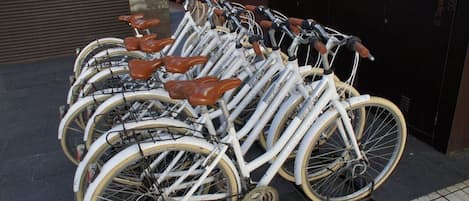Une rangée de vélos blancs avec des selles marron est garée contre un mur.