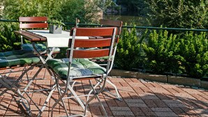 An outdoor seating area with a table and chairs, overlooking a river and a historic building. - Nassauer Hof Limburg (Limburg an der Lahn)