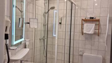 Un baño con ducha de mampara de vidrio, lavamanos e inodoro.