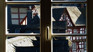 A door with a view of traditional European architecture, including a red and white half-timbered house and a grey house with a red roof. - Nassauer Hof Limburg (Limburg an der Lahn)