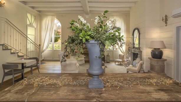 A spacious room with a large vase of flowers, a fireplace, and a staircase. - B&B Di Camilla (Pisa)