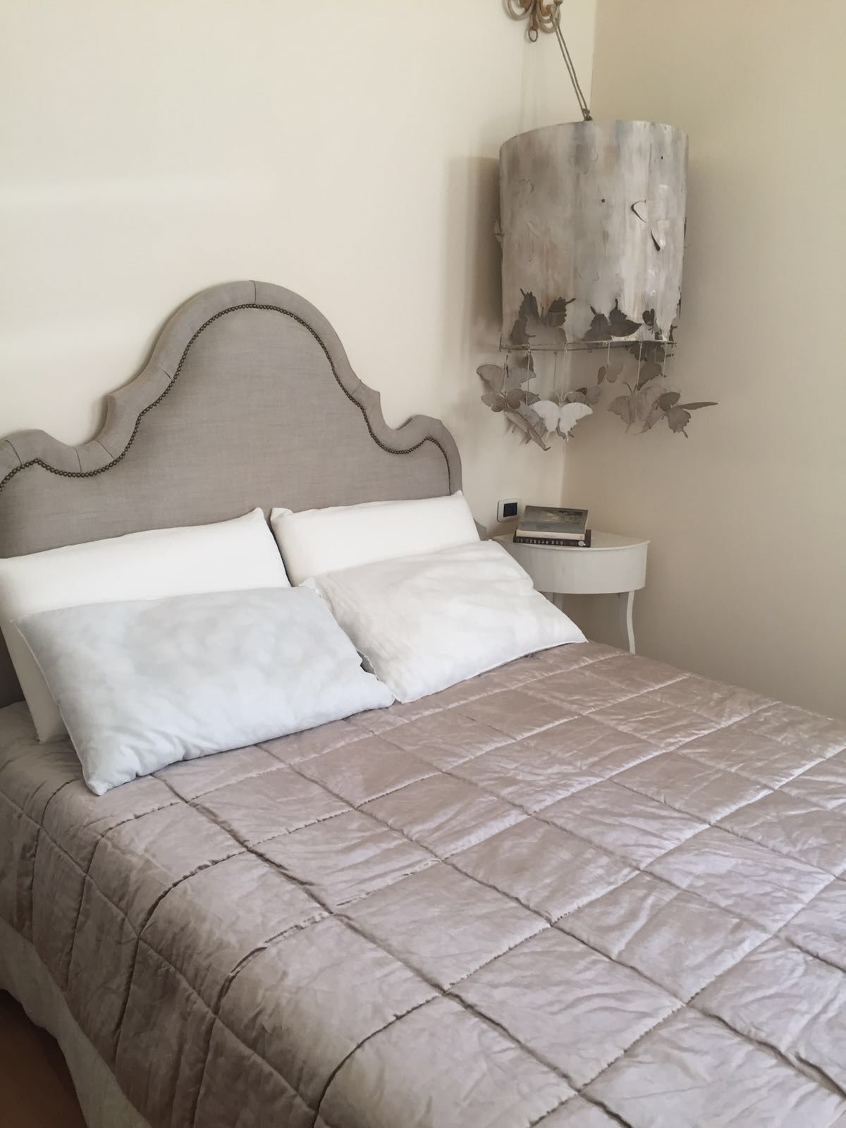 A bed with a quilted beige bedspread and a headboard with a chain detail.