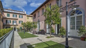 A courtyard with a paved walkway, green lawn, and potted plants. - B&B Di Camilla (Pisa)