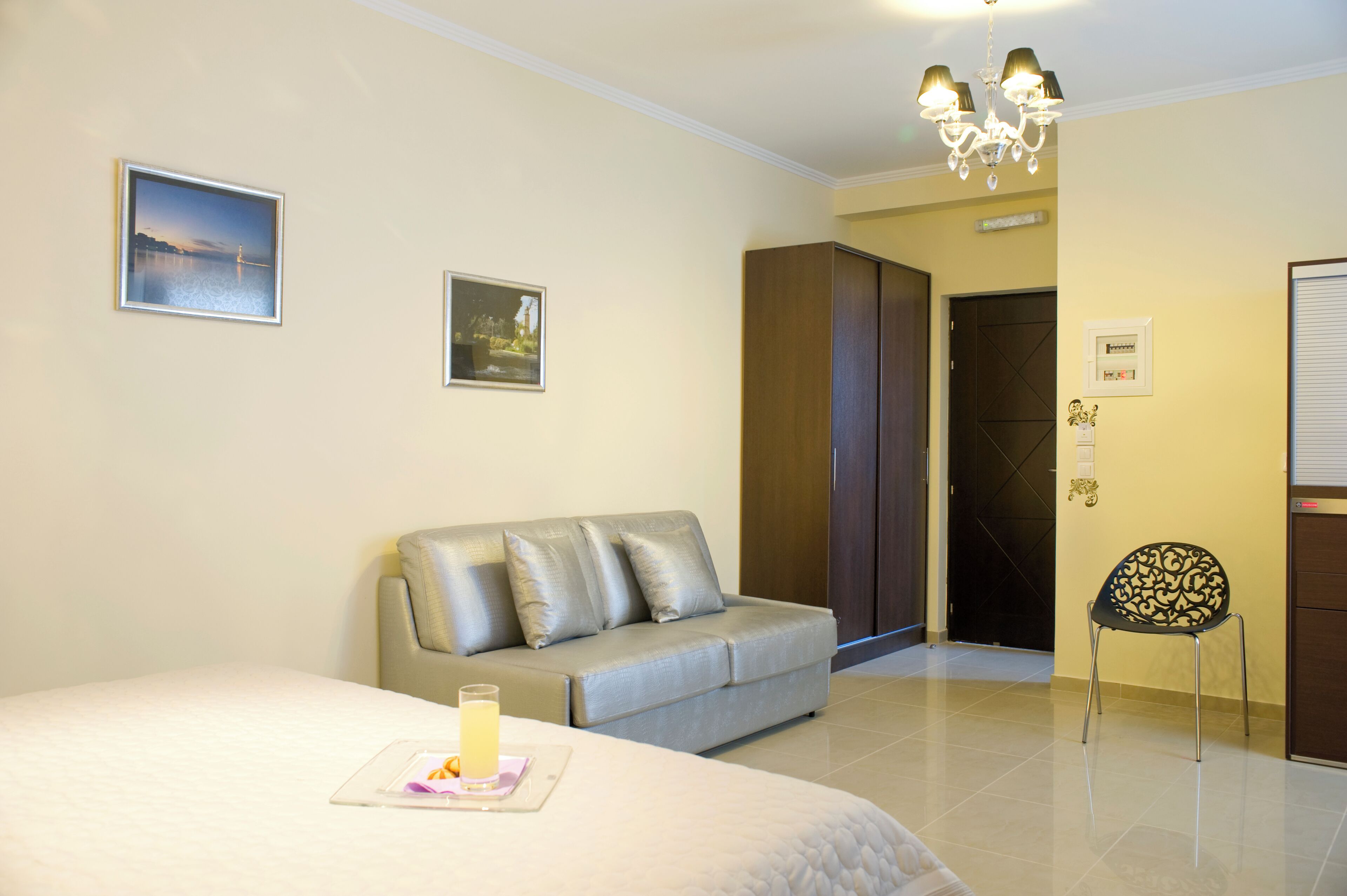 Una habitación de hotel con una cama, un sofá, una silla y un armario.