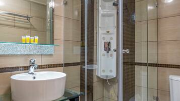Un baño moderno con ducha de vidrio, lavamanos blanco y un inodoro.
