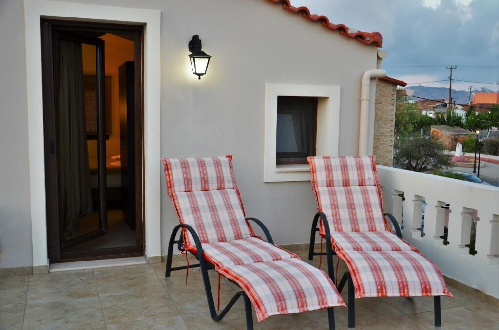 Un balcone con due poltrone a righe, una porta e un lampadario fissato al muro.