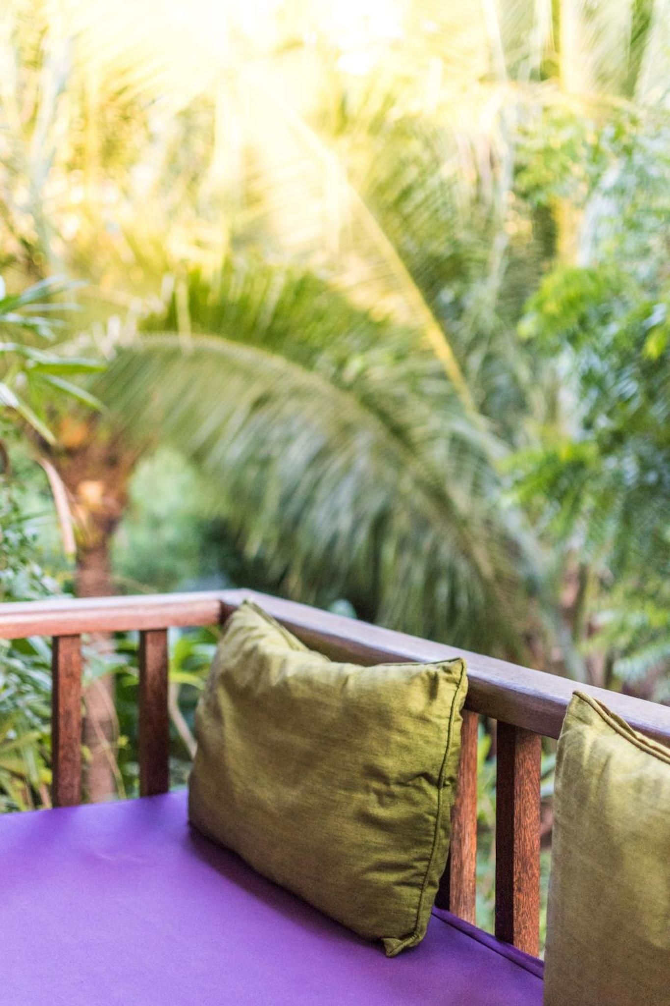 Una terraza de madera con un cojín morado y una almohada verde.