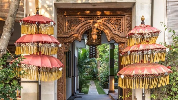 An ornate entrance with a wooden archway and decorative umbrellas. - Arjuna Homestay (Pemuteran)