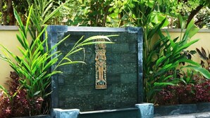 A pool with a decorative stone wall and a relief sculpture. - Arjuna Homestay (Pemuteran)