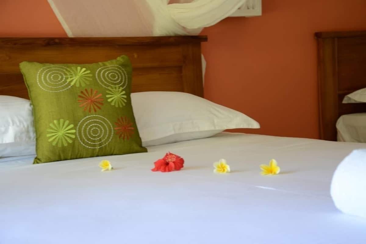 A neatly made bed with a green pillow, white pillows, and a white bedspread.