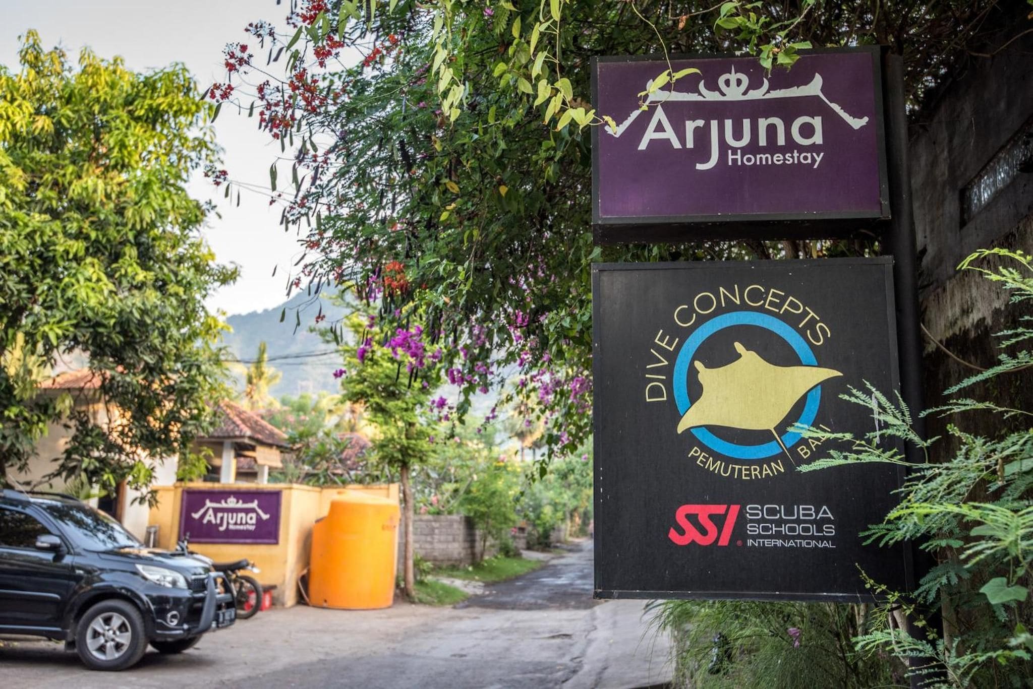 Señal para Arjuna Homestay con el logotipo de Dive Concepts y Scuba Schools International.