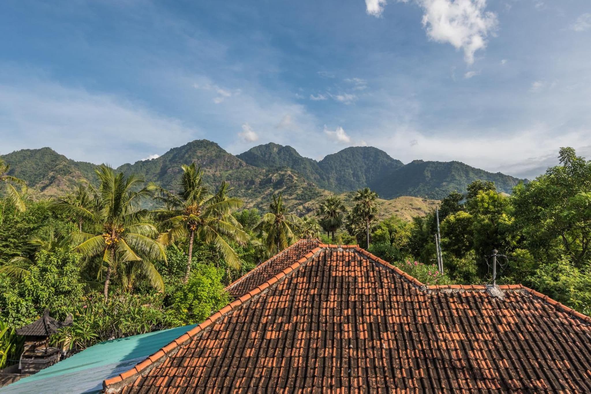 A traditional tiled roof, lush greenery, and a mountainous backdrop.