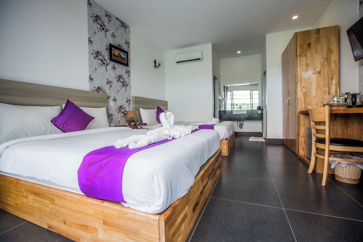 A hotel room with a large bed, a wooden desk, and a view of the outdoors.