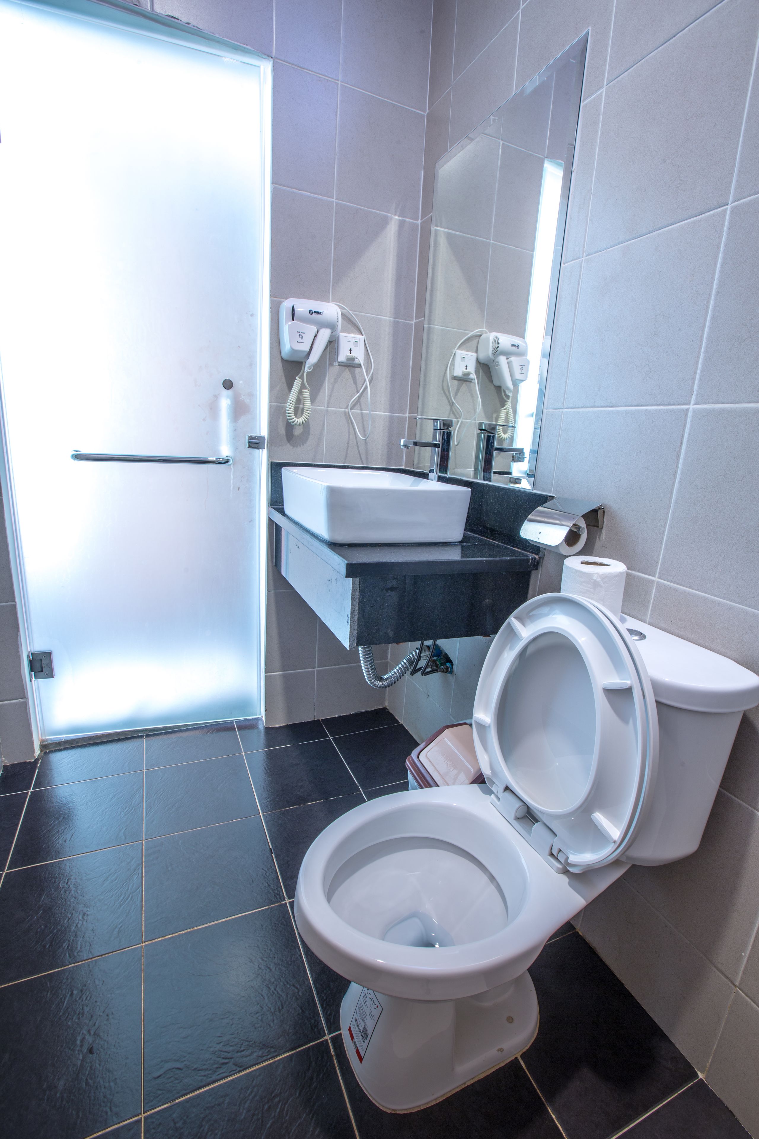 A bathroom with a toilet, sink, and a mirror.