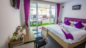 Een hotelkamer met een bed, een bureau met stoel, een televisie en uitzicht op het buitengebied.