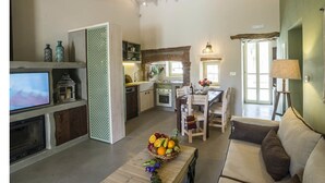 A spacious living area with a television, a dining table with chairs, a sofa, and a kitchen area with a dining table and chairs.