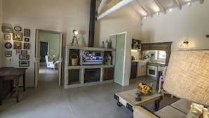 A spacious living area with a fireplace, a television, and a kitchen in the background.