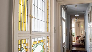 Un couloir orné de vitraux, d’un lustre et d’un tapis à motifs.