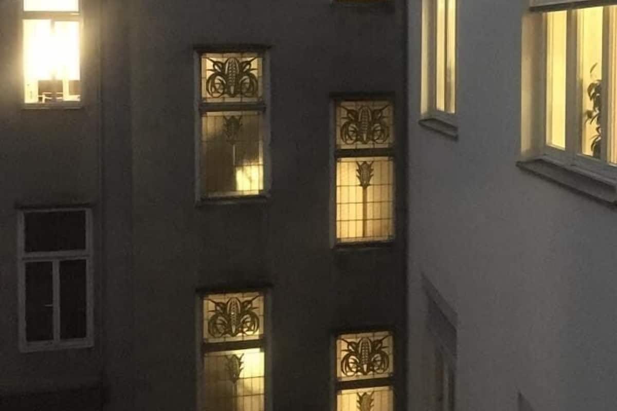 A multi-story building with uniformly designed windows, each featuring decorative metal grilles.