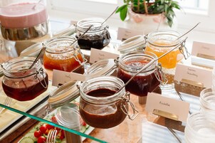 Buffet com vários potes de patês e acompanhamentos, cada um identificado com nomes como 'Honey', 'Nutella' e 'Sabugueiro'.