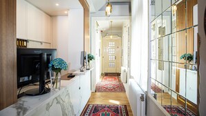Un couloir avec un plancher en bois, un tapis à motifs et un téléviseur posé sur un meuble.