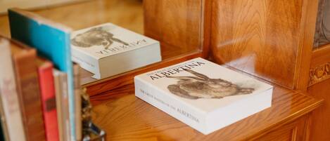 A wooden desk with a book titled 'The Great Masters of the Albertina' and a mirror reflecting the book.