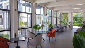 Un espace intérieur vaste et lumineux, doté de grandes fenêtres, de nombreux coins salon et de plantes d’intérieur.