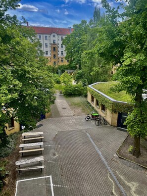 A courtyard with a paved area, a bicycle, and a building with a red roof in the background. - Pension Freiraum Guesthouse Berlin (Berlin)