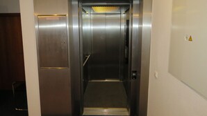 An elevator with a metallic finish, a safety sign, and a warning label. - Pension Freiraum Guesthouse Berlin (Berlin)
