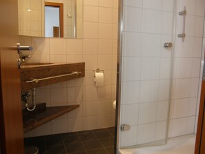 A bathroom with a shower, a sink with a towel rack, and a toilet. - Pension Freiraum Guesthouse Berlin (Berlin)