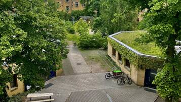Ein Innenhof mit befestigtem Boden, einem Fahrrad und einem Gebäude mit rotem Dach im Hintergrund.