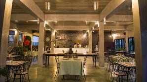 An interior view of a restaurant with a brick wall, tables, chairs, and a counter. - Maryo Resort Chiangrai (Chiang Rai)