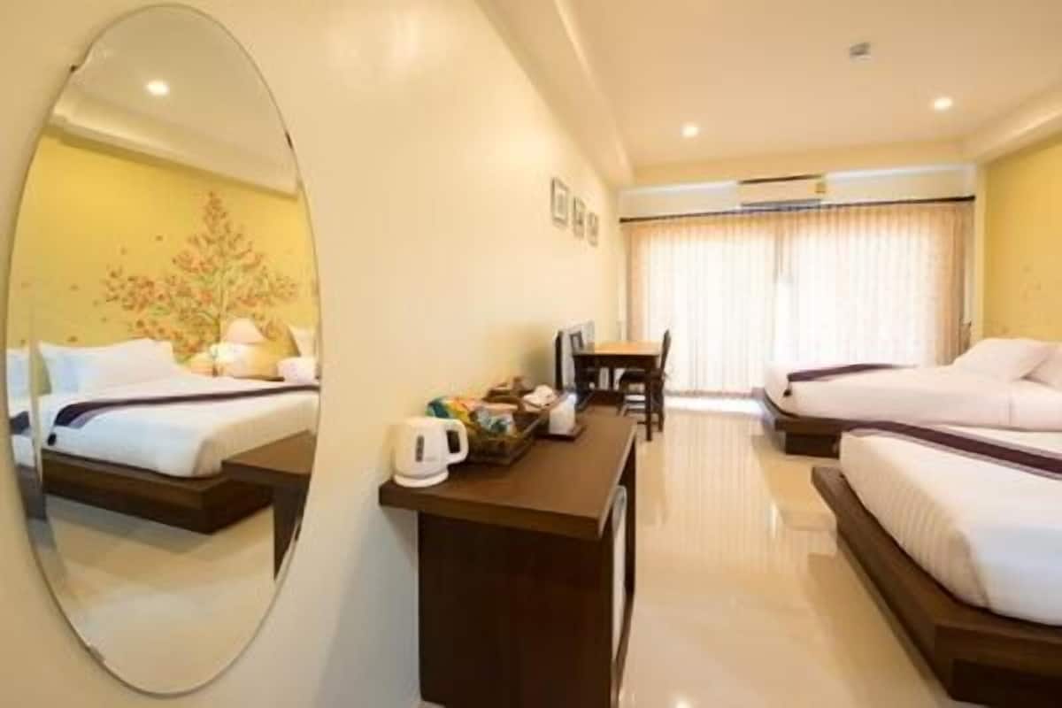 A hotel room with two beds, a desk with a coffee maker, a chair, and a large mirror.