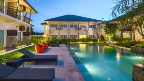 A swimming pool with lounge chairs and a building with multiple windows and air conditioning units. - Maryo Resort Chiangrai (Chiang Rai)