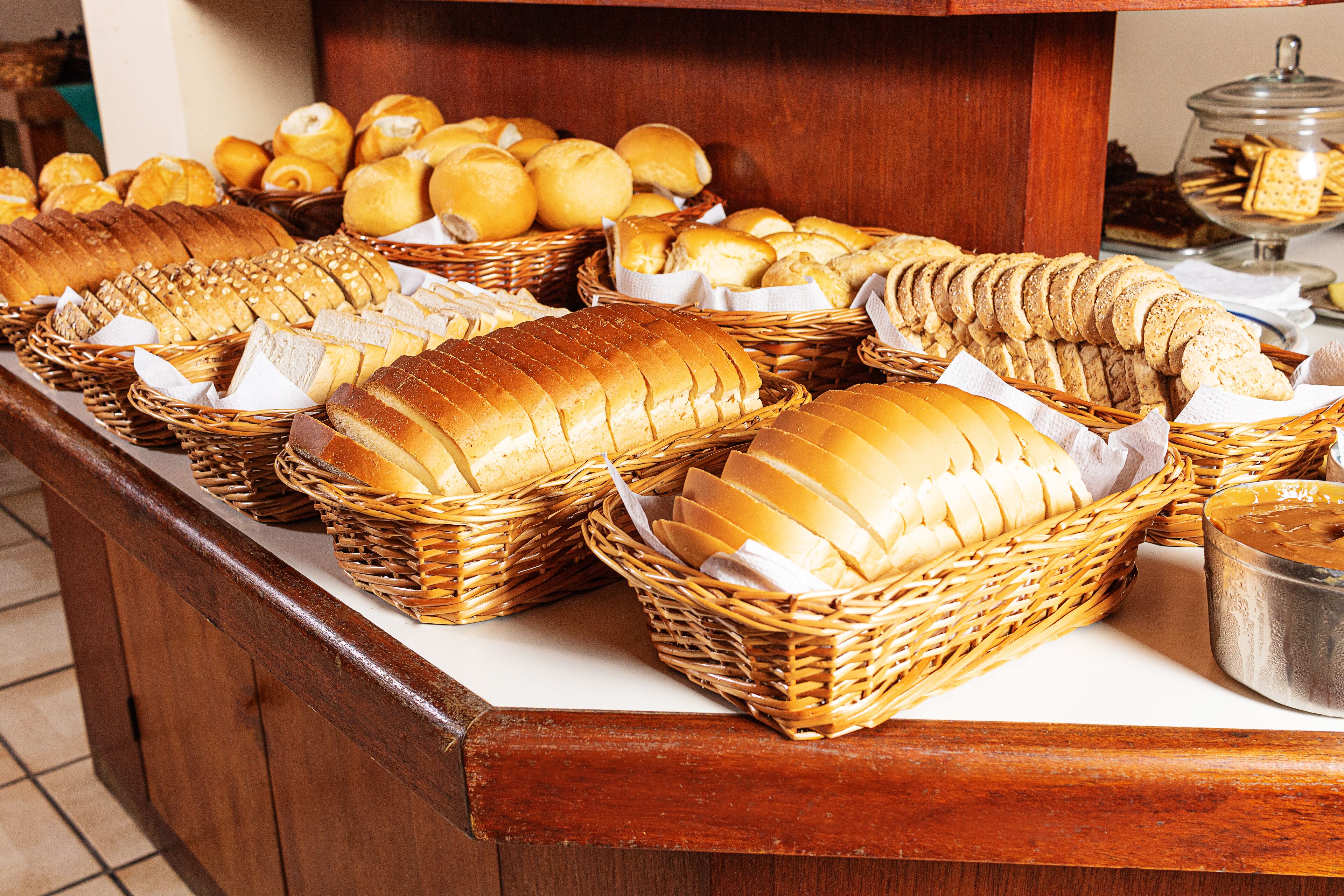 Un bufé con panes y pasteles diversos expuestos en cestas de mimbre.