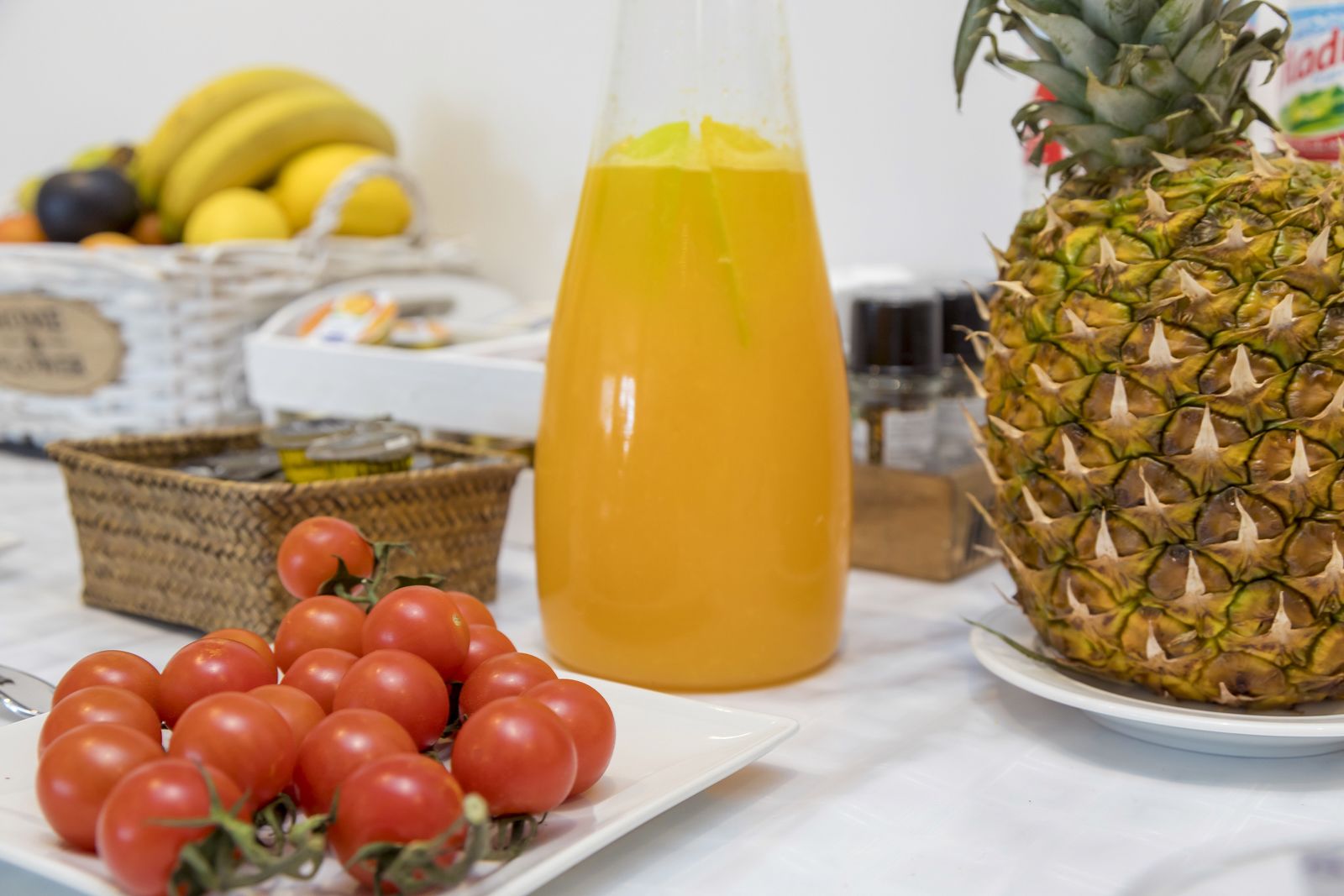 Ein Tisch mit Orangensaft, einer Ananas und einer Tomatenschale.