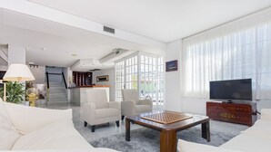Un salon moderne comprenant un canapé, des fauteuils, une table basse et un téléviseur.