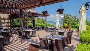 An outdoor patio with wicker furniture and tables, overlooking a scenic view.