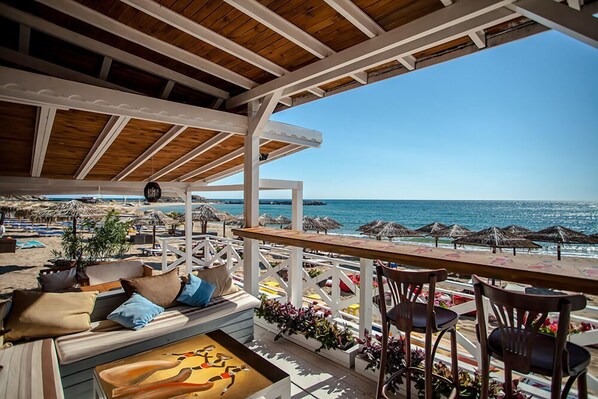 Eine Terrasse am Strand mit Holzmöbeln, Sonnenschirmen und Blick aufs Meer.