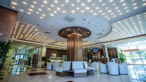 A modern lobby with a central seating area, a glass storefront, and a ceiling with recessed lighting.