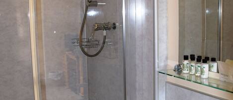 Un baño moderno con cabina de ducha de vidrio, un lavabo blanco y un espejo sobre el lavabo.