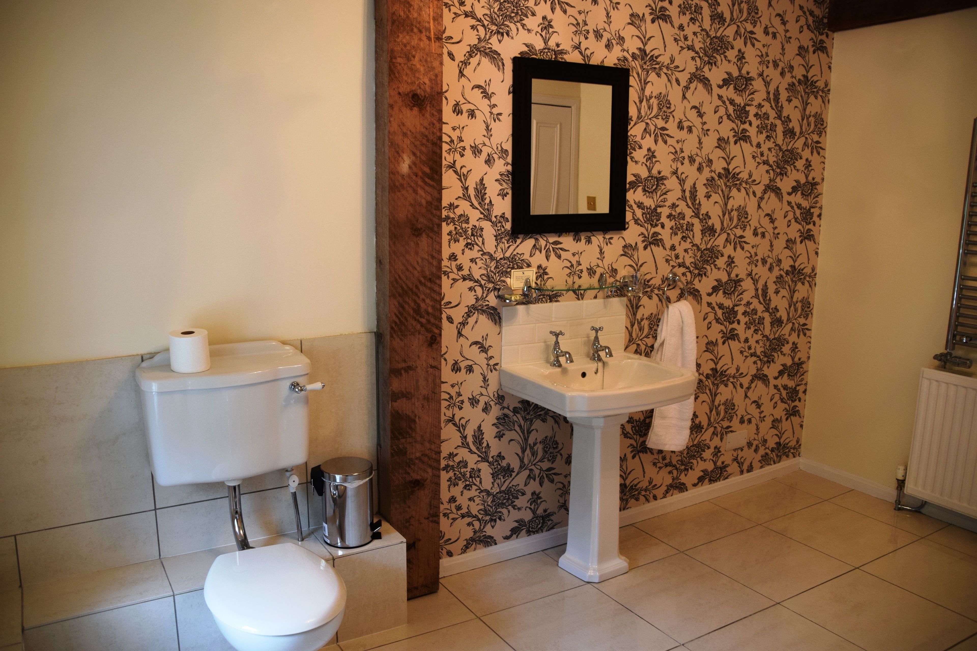 A bathroom with a toilet, sink, and mirror.