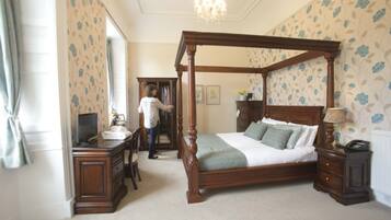 A bedroom with a four-poster bed, a desk with a computer, and a dresser.