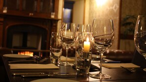 Une table à manger dressée avec des verres à vin, une bougie et des couverts.